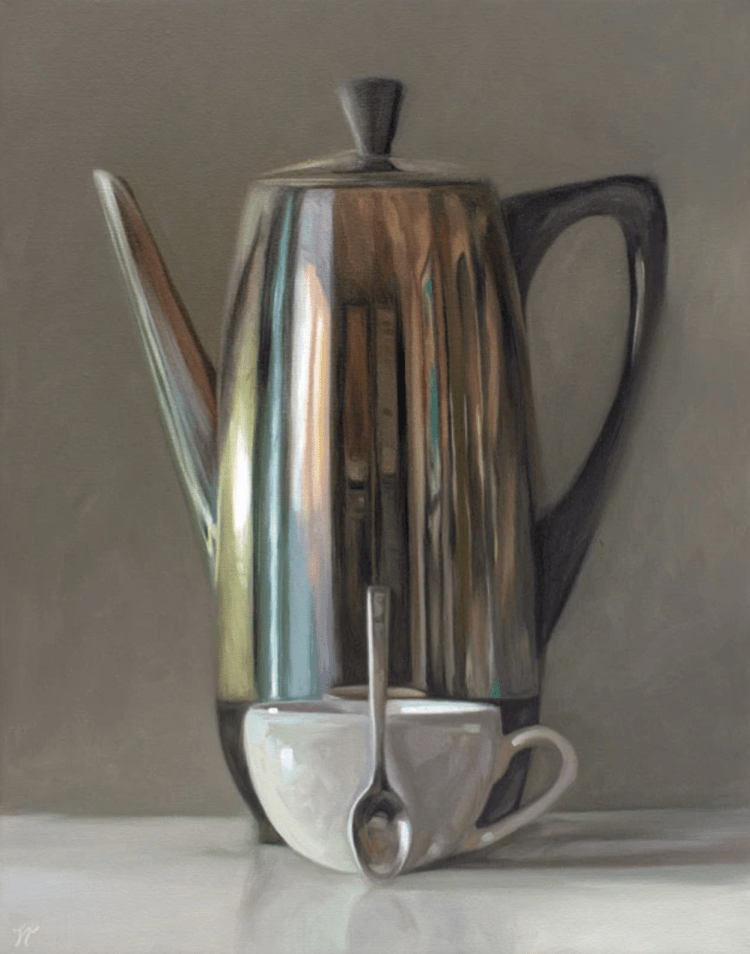 A coffee percolator rests on a light, reflective surface accompanied by a porcelain coffee cup and mini spoon.